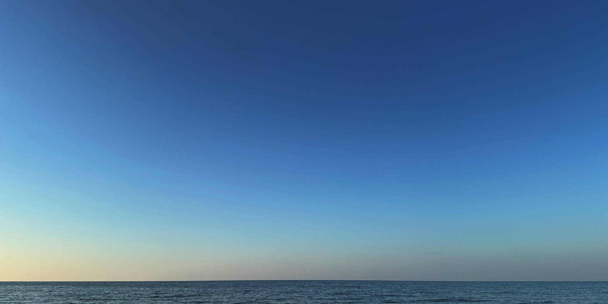 Lake horizon beneath a wide blue evening sky.