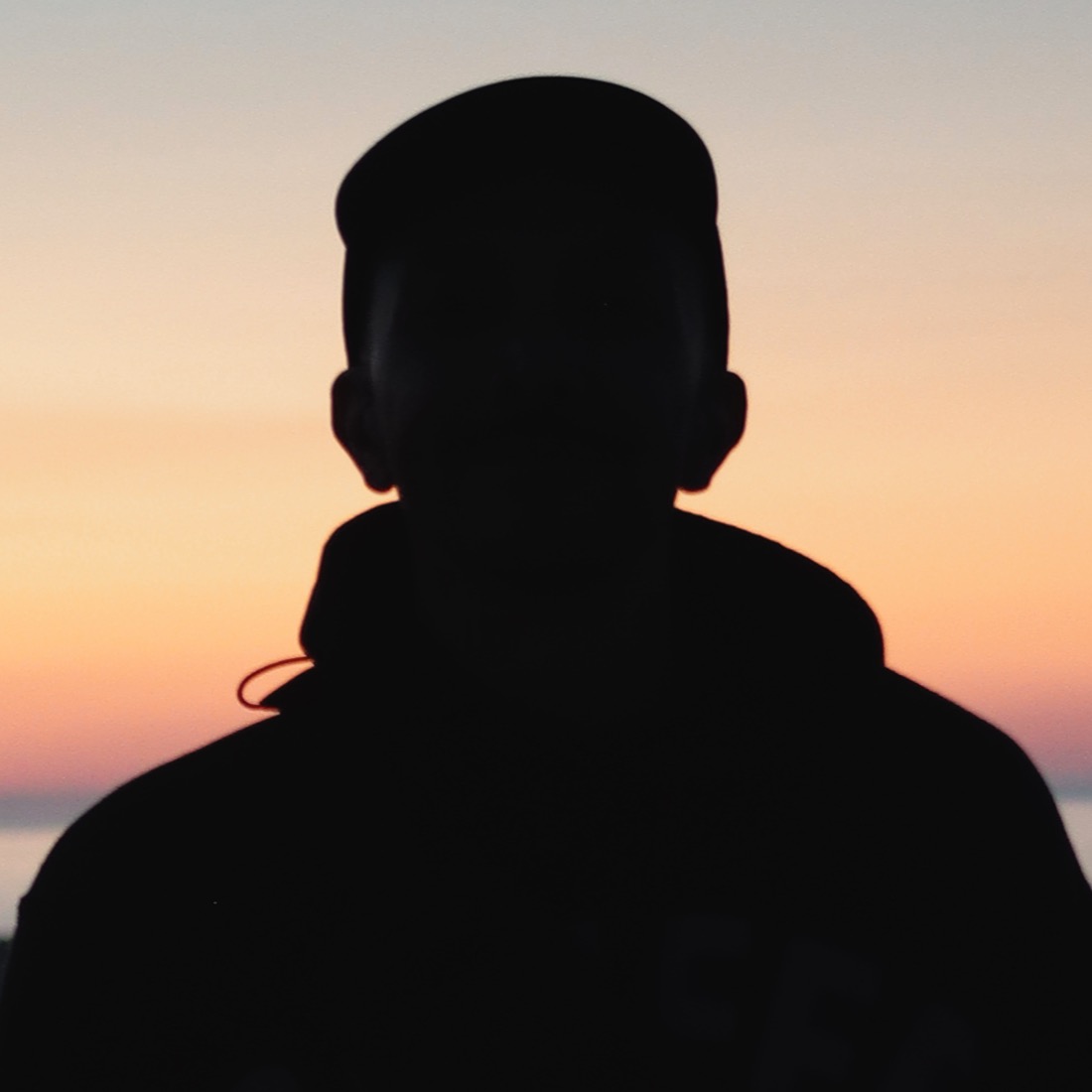 Derek Jerome silhouetted against an orange and pink sunset.