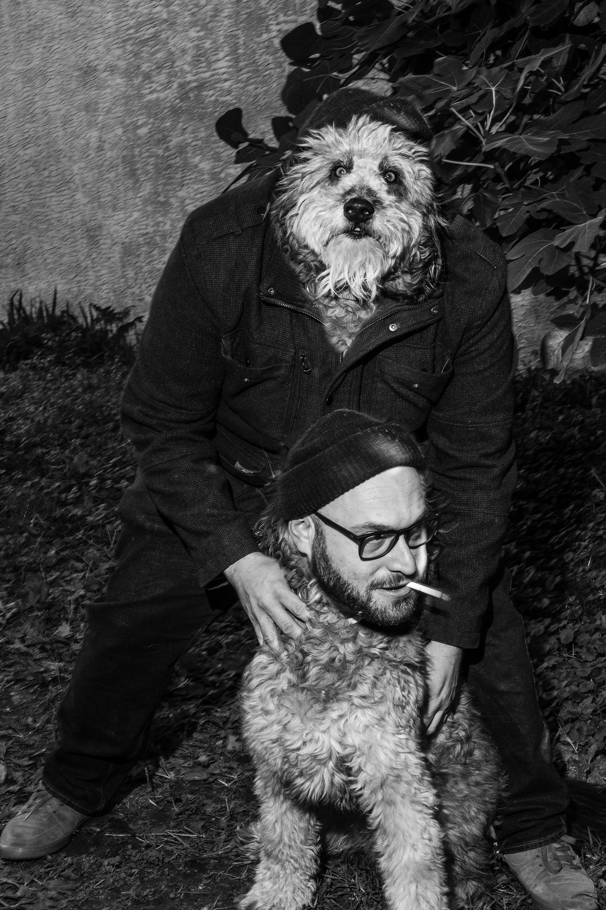 Black-and-white night photograph of Jordan Baumgarten crouched with Walter in the back lot.