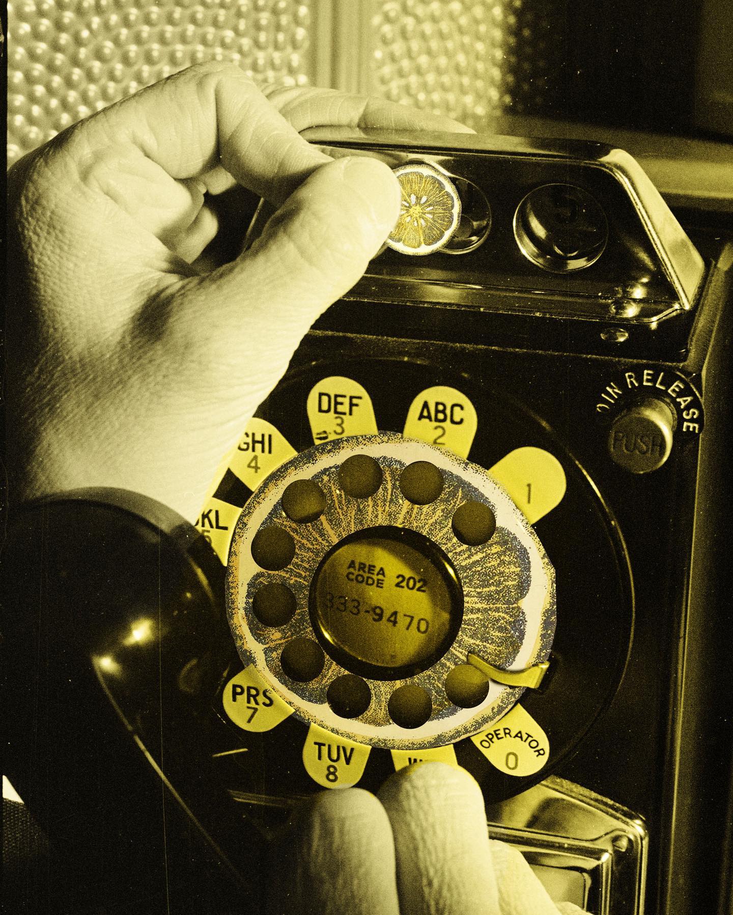 A hand dialing a rotary telephone in an early Lemon Juice identity-making image.